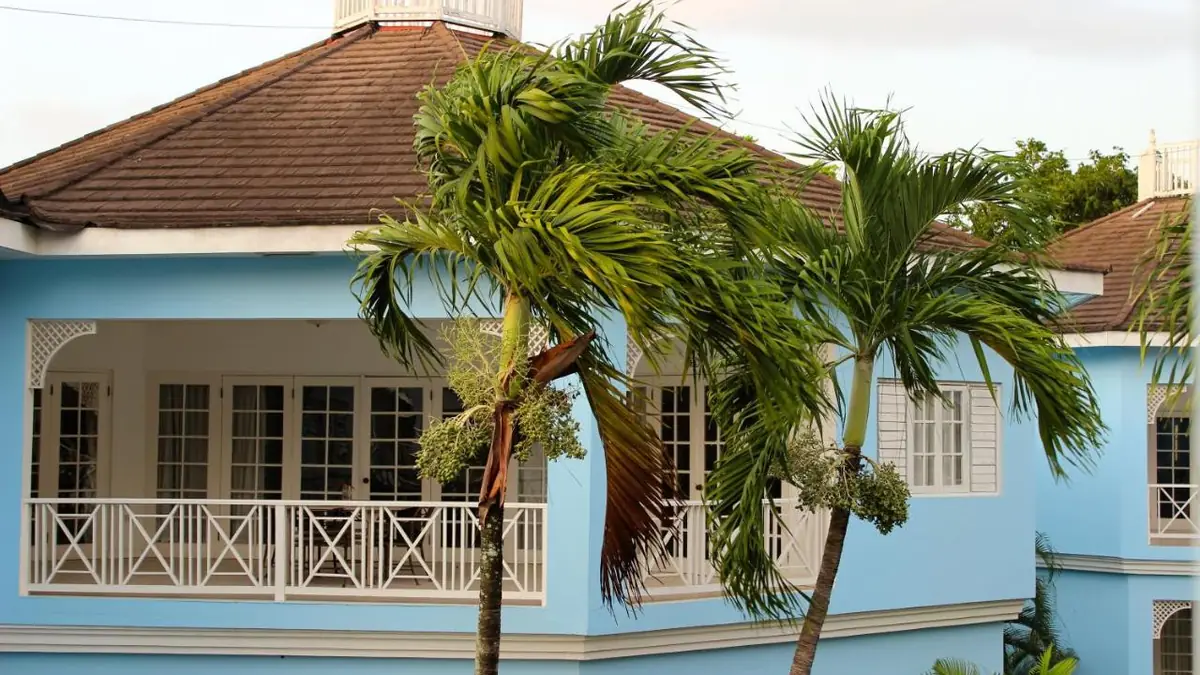A building at Beachcomber Club Resort, light blue with white balconies and palm trees